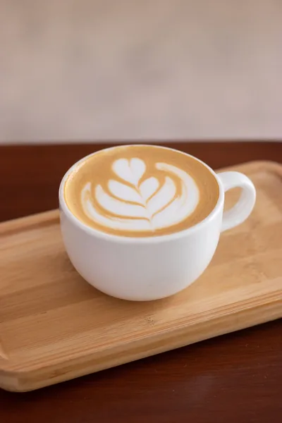 Café com leite numa chávena branca, com uma tulipa desenhada na espuma